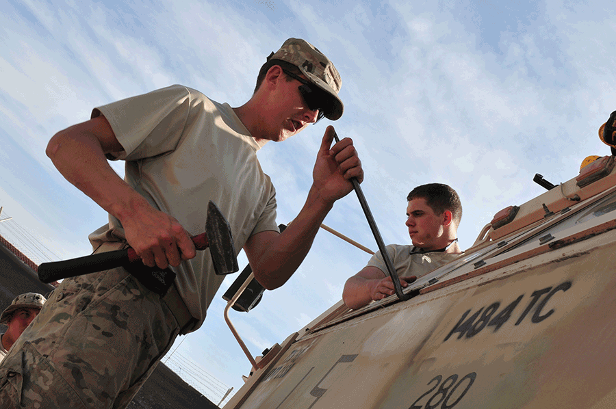 Soldiers work on vehicle.