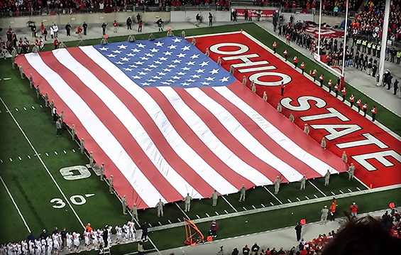 About 40 Ohio National Guard Soldiers and Airmen wave a large American flag over the field at Ohio Stadium.