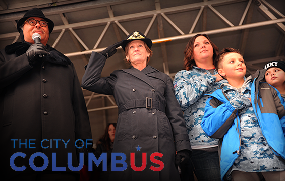 Columbus Mayor Michael Coleman (from left), Maj. Gen. Deborah A. Ashenhurst, Ohio adjutant general, and the Family of Myles Eckert salute the American flag as it passes by the reviewing stand during the Columbus Area Veterans Day Parade.