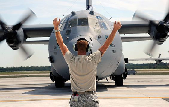 Tech. Sgt. Mark Dulworth, a crew chief with the 179th Airlift Wing, marshals in a C-130 Hercules on the flight line.