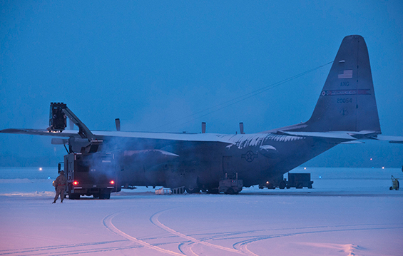 Airmen work during the early morning to remove snow from the flight line and fleet of C-130H Hercules.
