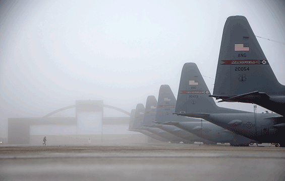 Master Sgt. Kristopher Wolf walks through a blanket of fog settled over the fleet of C-130H Hercules.