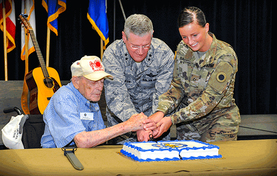 Maj. Gen. Mark E. Bartman is assisted by World War II veteran Edgar Morman  and Pfc. Gabrielle Babbitt in making the first cut in the cake during the 229th Ohio National Guard birthday celebration.