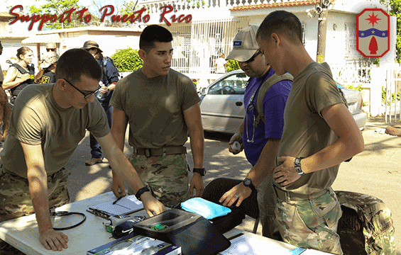 Three Army health care specialists prepare a triage station on a residential street.

