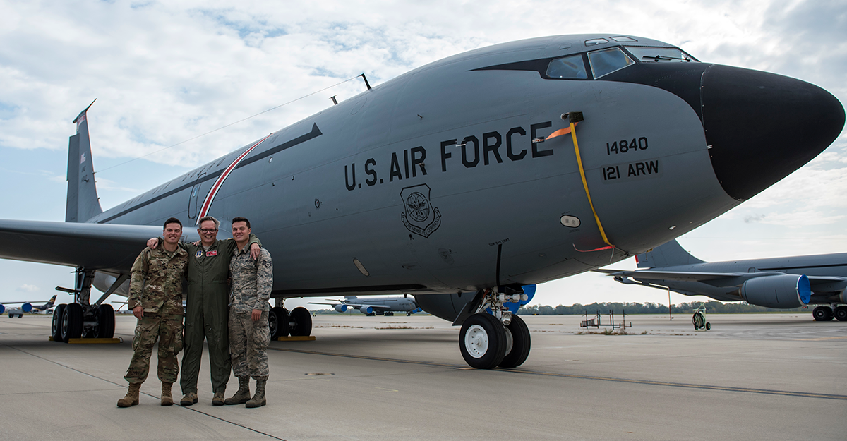 Three airmen pose in front of aircraft.