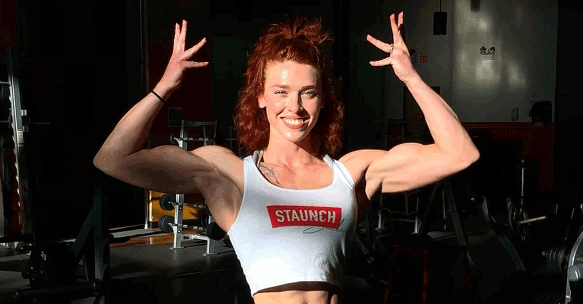 Female bodybuilder poses in gym.