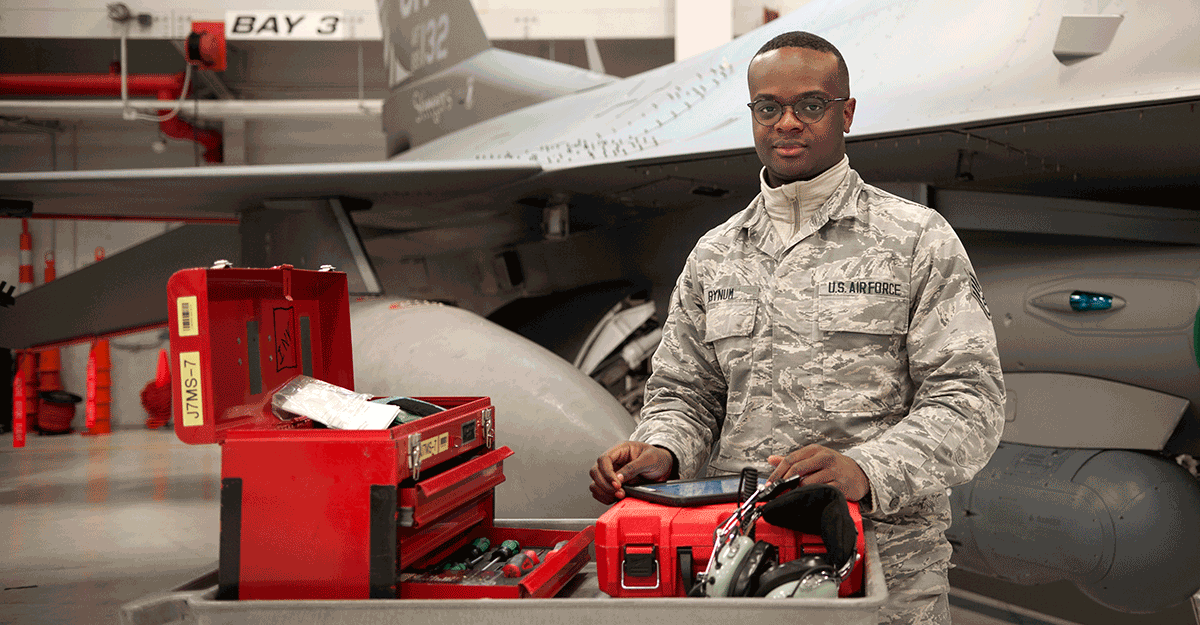 Bynum stands in front of f-16 with toolbox.
