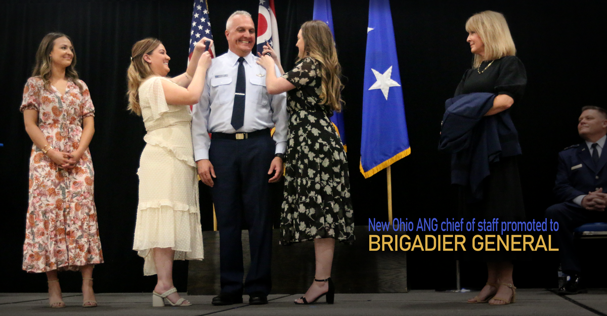 Johnson on stage with daughters pinning stars on his shoulders.