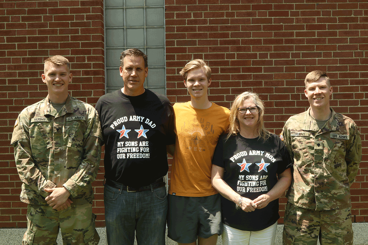 Family pose for pic with 2 Soldiers. T-shirts read -PROUD ARMY MOM/DAD MY SONS ARE FIGHTING FOR OUT FREEDOM 