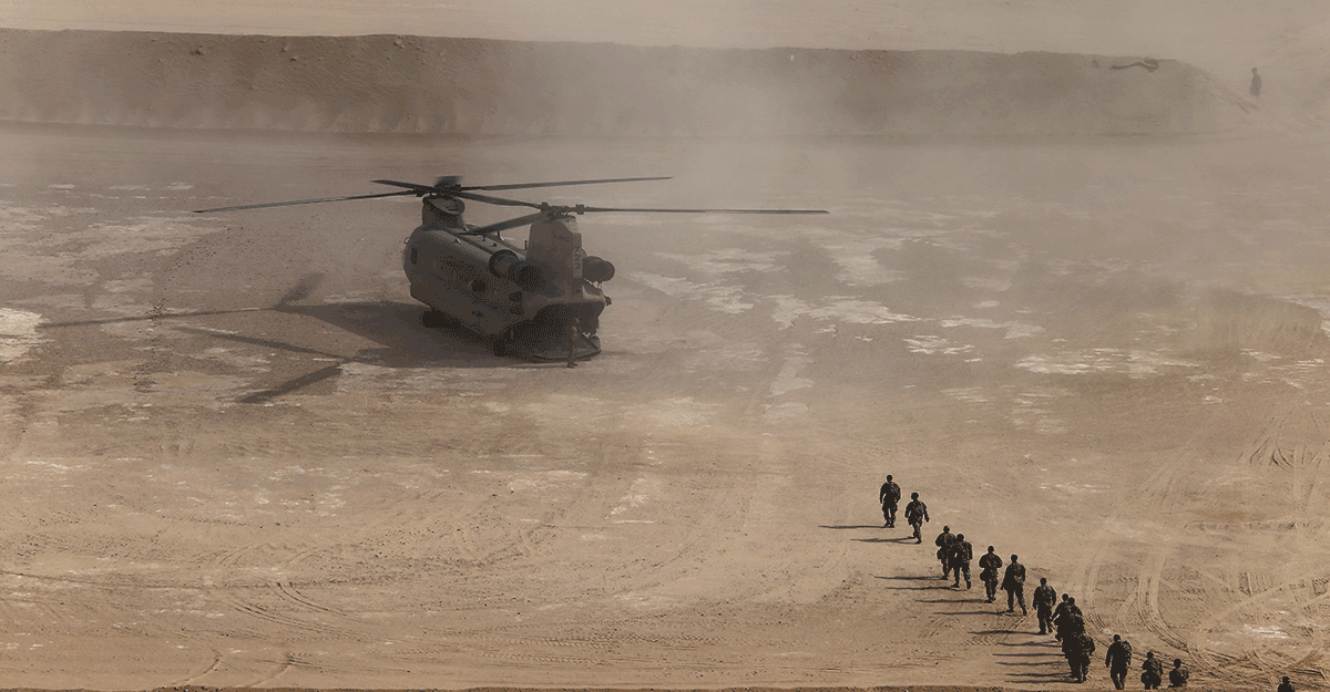 CH-47 Chinook in dessert with line Soliders approaching for loading.