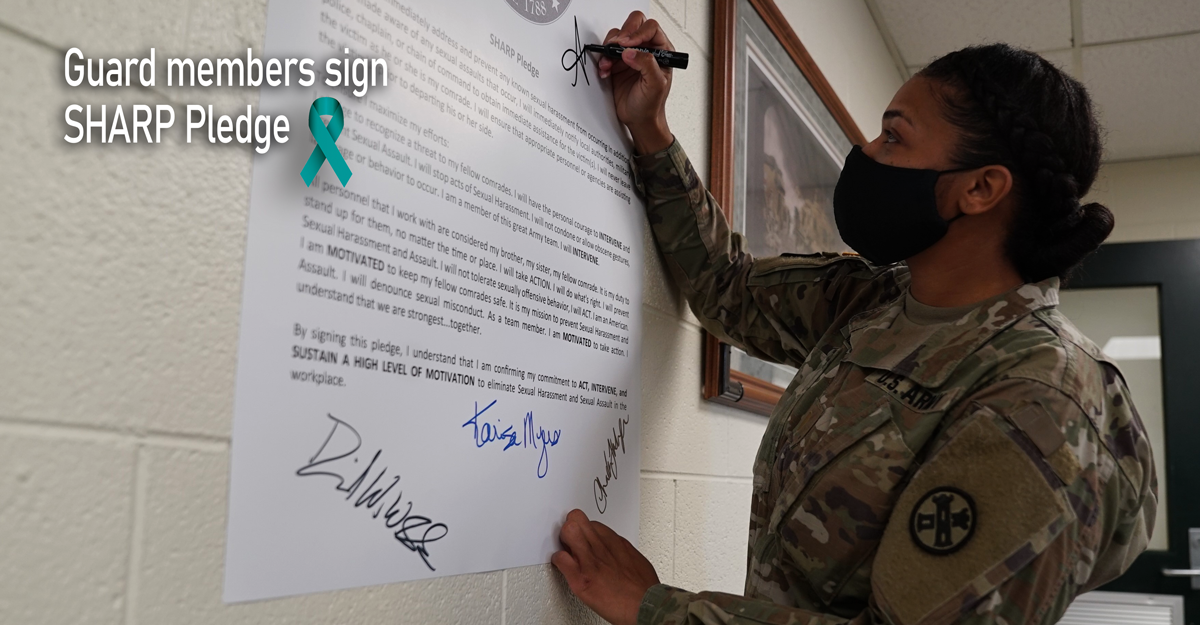Female solder signs pledge on wall.