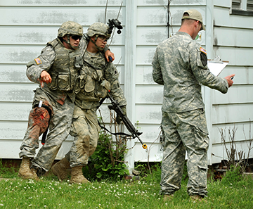 Staff Sgt. Sean McGreevy (center) of Company B, 1st Battalion, 148th Infantry Regiment and a Swanton, Ohio, resident, carries a Soldier role-playing as a casualty during the urban operations lane of the Expert Infantryman Badge (EIB) qualification.