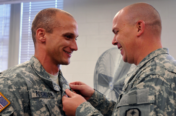1st Sgt. Christopher Thomas (right) of the 285th Medical Company (Area Support) out of Columbus, Ohio, pins an Army Achievement Medal on Staff Sgt. Heath Robinson, a squad leader for the 285th, and a Canal Winchester, Ohio, native