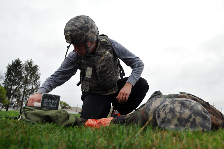 A Soldier with the 371st Special Troops Battalion applies a tourniquet to the arm of Pfc. Kelly Franz