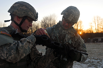 Sgt. Brian J. Brewster applies cleaning, lubricant and protectant fluid to the M4 carbine of Spc. Quinn M. Izar, a Chardon