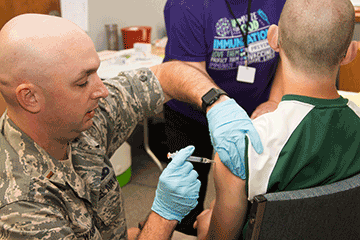 Second Lt. Christopher Warman, a nurse with the 121st Air Refueling Wing, administers a vaccination booster shot to a Noble County resident.