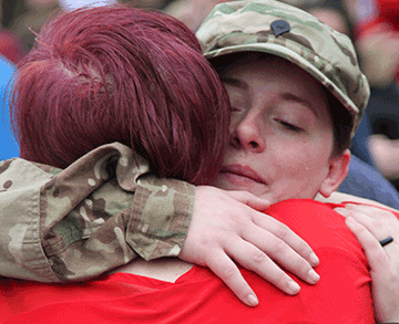 Spc. Cailin Hoskins, an AN/TWQ-1 Avenger Air Defense System crew member, hugs a loved one before loading the bus.