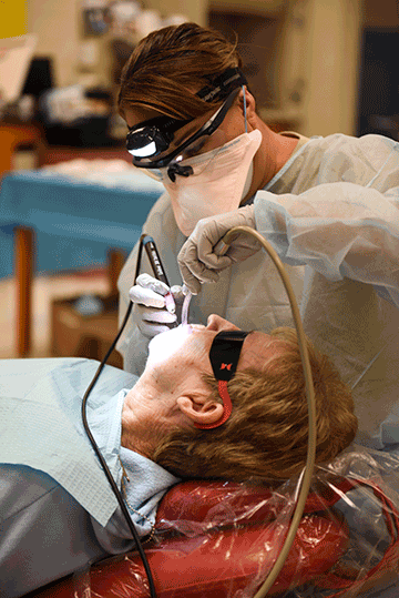 Air Force Master Sgt. Kristie Blumer cleans a patient’s teeth.