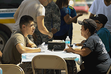 Spc. Victor Guerrero assesses a patient at a temporary medical outreach station.