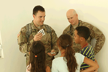 Capt. Calebb Proehl, a chaplain attached to the 285th Medical Company (Area Support), does a card trick for children.