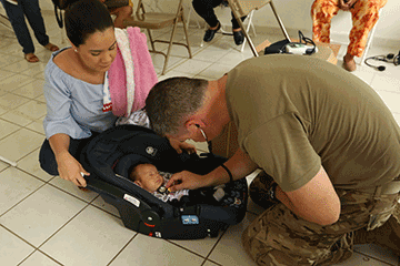 Staff Sgt. Matthew Crabtree, a medic with the 285th Medical Company (Area Support) and a registered nurse, performs a medical assessment on an infant less than one month old.