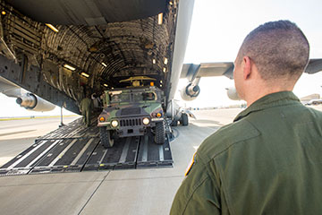 An Airman guides an Ohio Army National Guard Humvee onto a C-17 Globemaster III.