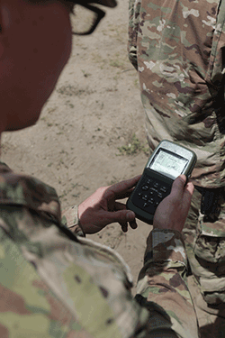 View over Soldier's shoulder looking at hand held device.