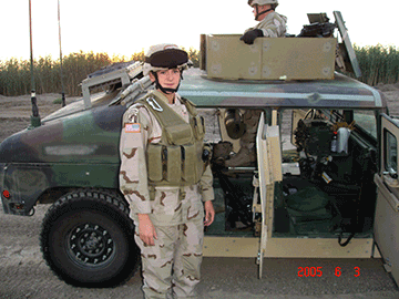 Capt. Jennifer Mitchell stands in front of military vehicle.