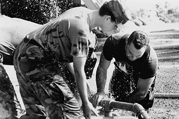 Black and white photo of soldiers assembling water purification equipment in 1993.