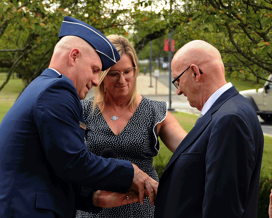 Brig. Gen. Gary McCue  presents a general officer’s star rank to his father-in-law as his wife looks on.
