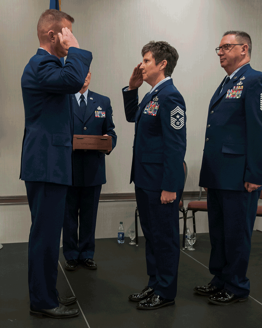 Chief Master Sgt. Heidi Bunker salutes Brig. Gen. Todd Audet with Chief Master Sgt. Thomas Jones.