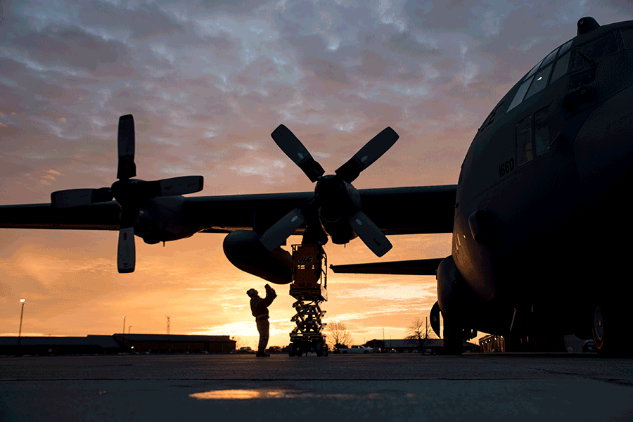 airman works on aircraft on tarmack at sunset