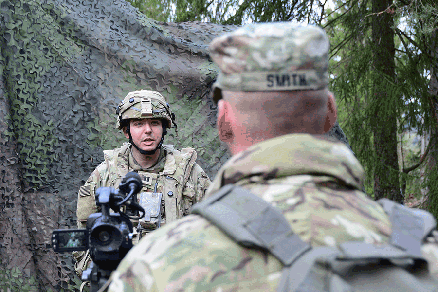 Soldier with camera talks to Soldier in woods