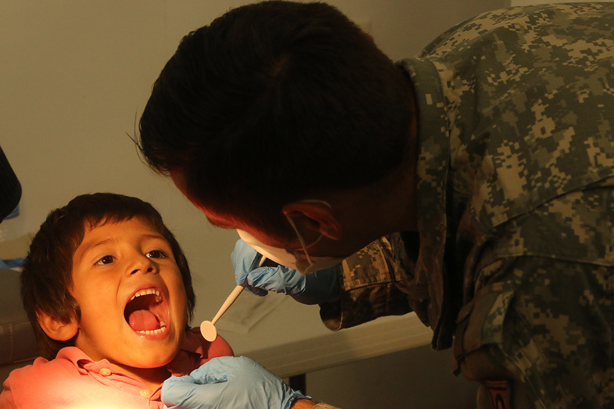 Soldier tends to child in dentist chair