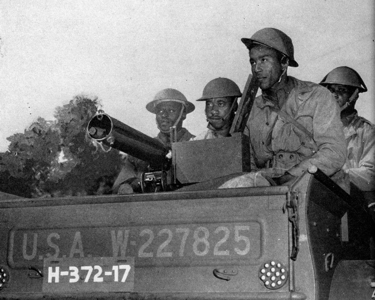 African-American Soldiers pose around guns.