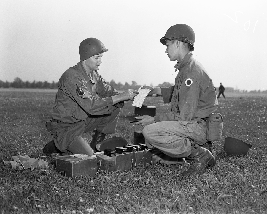 Black and white photo of Soldiers kneeling in field.
