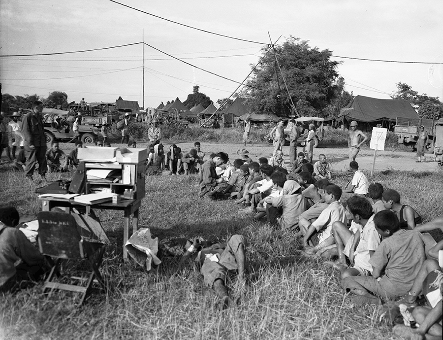 Japanese soldiers sit in rows in field outside of camp waiting to be processed. 