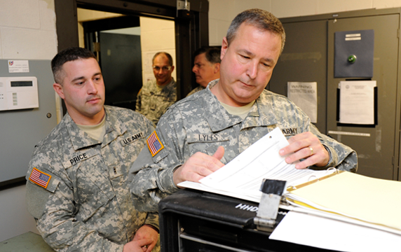 Chief Warrant Officer 2 Brady Price (left), property book officer for Headquarters, 155th Chemical Battalion, looks over the shoulder of Chief Warrant Officer 4 William Lyles, Army National Guard senior warrant officer adviser at the Ordnance Corps and School in Fort Lee, Va.