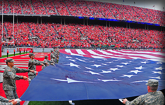 About 50 Ohio National Guard Soldiers and Airmen wave a large American flag over the field at Ohio Stadium during the national anthem before The Ohio State University's game with Florida A&M Sept. 21, 2013, in Columbus, Ohio. OSU honored and hosted about 300 ONG Soldiers and Airmen as part of its annual military appreciation game.