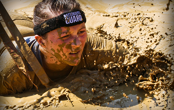 Second Lt. Mary Kauffman of the 112th Transportation Battalion crawls through mud during the Warrior Dash.