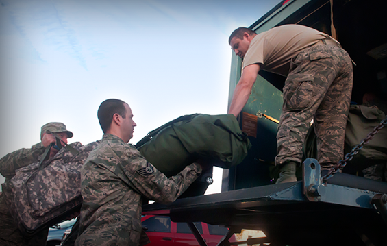 Airmen with the 121st Air Refueling Wing load fellow members' luggage into a transportation vehicle during a "bag drag".