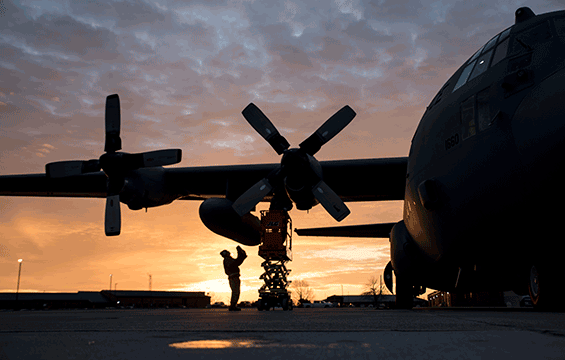 Silhouette of mechanic working on C-130H at sunrise