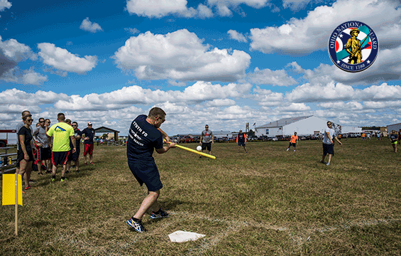 Airmen playing baseball in field wearing civilian clothing.
