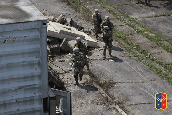 Armed Soliders canvassing around rubble and metal building.