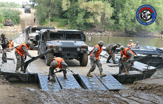 military vehicles are transported across water on a barge