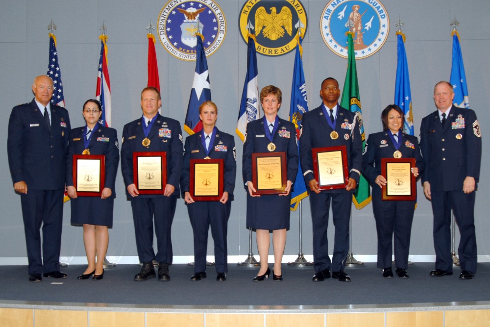 Airmen of the year stand on stage with awards.