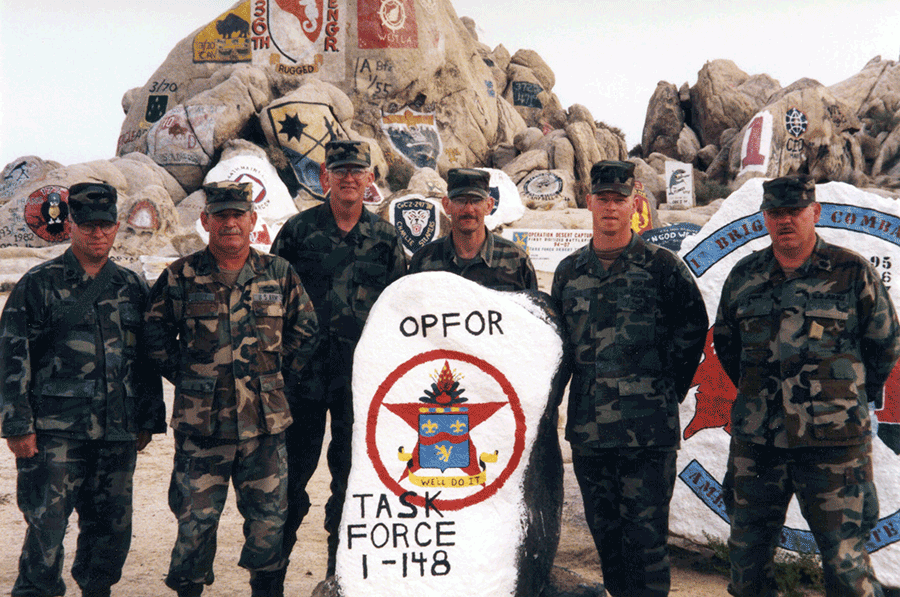 Soldiers stand around painted rock for group photo.