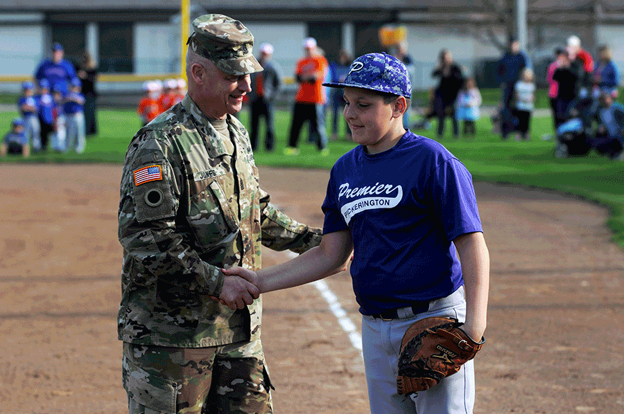Uniformed Jones shakes hands with youth baseball player on diamond.