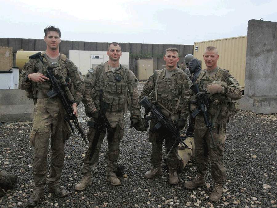 Soldiers stand for group photo outside building.