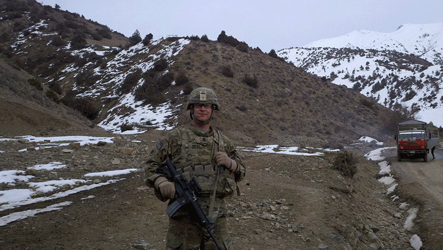 Jones stands in forefront of snow covered mountains in full camo.